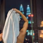Жена подсушава косата си след вечерен душ
